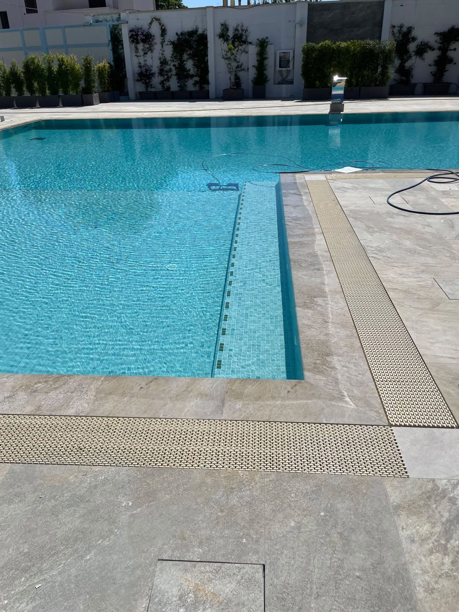 Piscina rivestita in mosaico vetroso azzurro con bordo in pietra