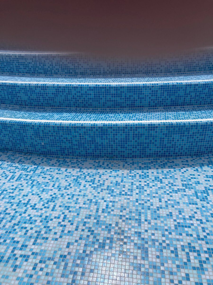 Gradini di una piscina rivestiti in mosaico con sfumatura azzurra
