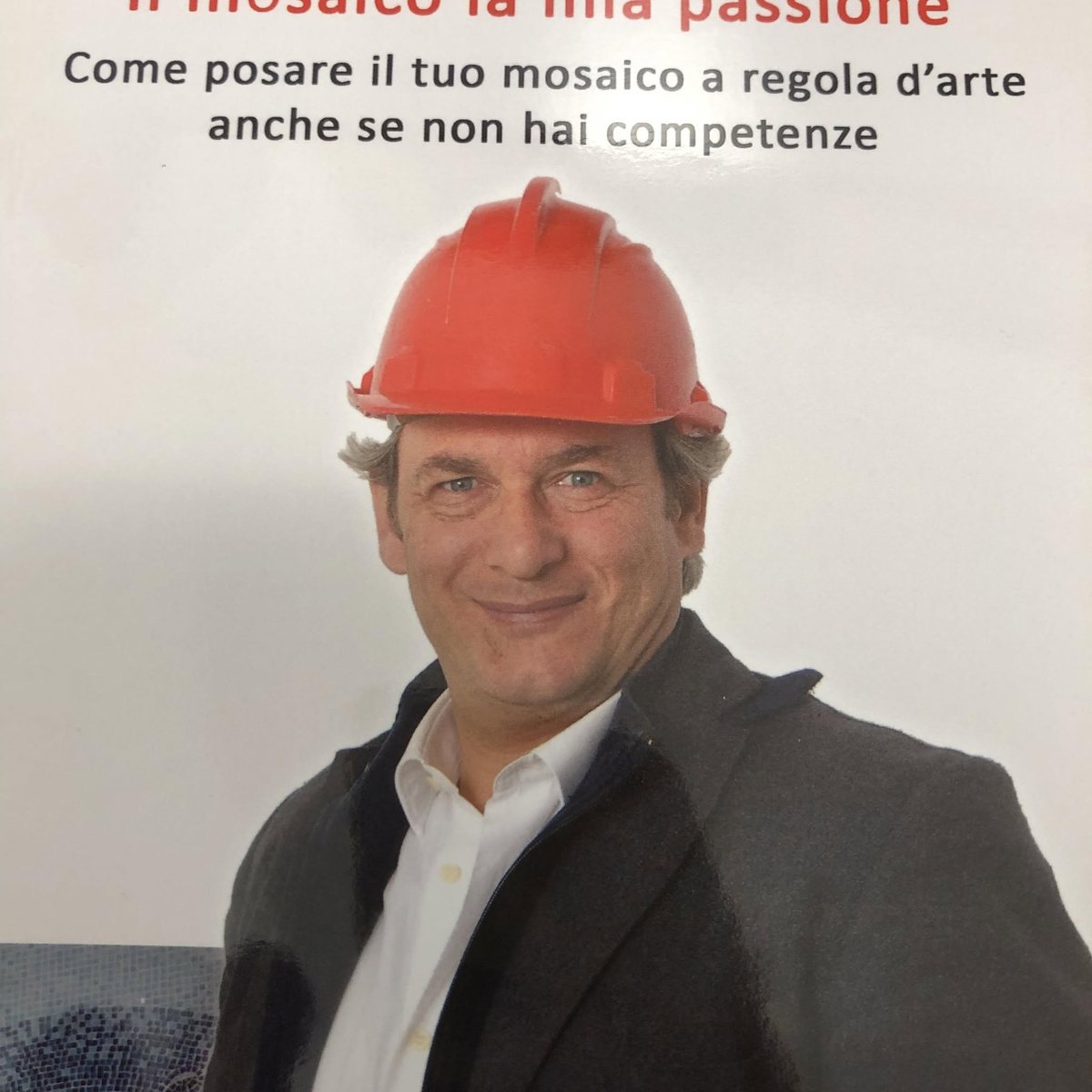 Copertina del libro «Il mosaico la mia passione»: uomo sorridente con casco rosso, giacca scura e camicia bianca